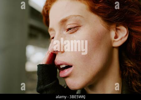 Image en gros plan montrant le moment émotionnel d'une femme avec une larme sur sa joue. Main de femme près de son visage ajoutant un sentiment de contemplation et de vulnérabilité Banque D'Images