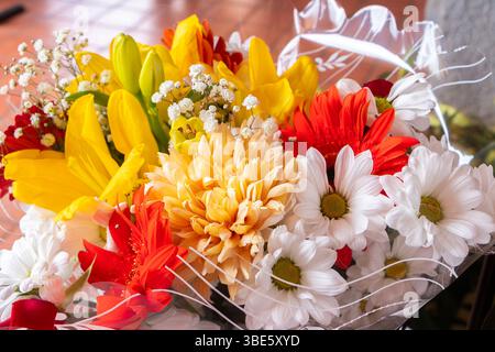Bouquet vibrant de fleurs assorties comprenant des lis, des marguerites, des gerbera et des roses dans des couleurs vives jaune, rouge et blanc Banque D'Images