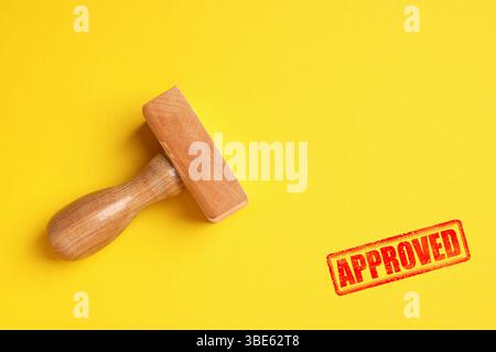 Timbre rouge approuvé et timbre en bois sur fond jaune, vue de dessus Banque D'Images