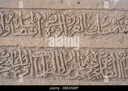 La calligraphie arabe complexe sculptée dans la pierre présente de beaux œuvres d'art islamique et des inscriptions religieuses à la mosquée historique Al Khamis à Bahreïn. Banque D'Images