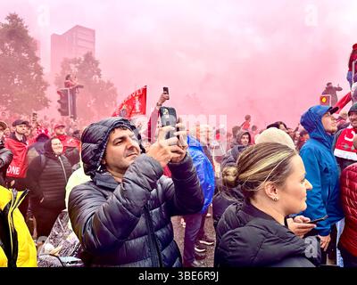 Fan filme le bus défilé du Liverpool FC sur Strand Street alors que la fumée rouge remplit l'air et que les foules célèbrent. Liverpool, Royaume-Uni. 26 mai 2025. Banque D'Images