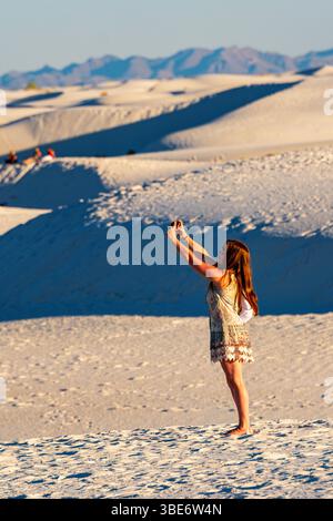 Jeune femme prenant une photo selfie iPhone sur les dunes de sable au White Sands National Park ; Nouveau-Mexique ; États-Unis Banque D'Images