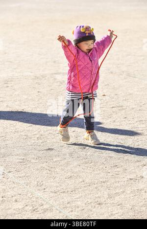 Enfant en bas âge imitant une corde à sauter Banque D'Images