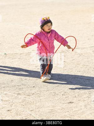 Enfant en bas âge imitant une corde à sauter Banque D'Images