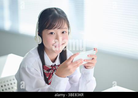 Filles du secondaire qui suivent des cours avec des smartphones Banque D'Images