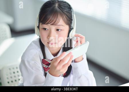 Des filles du secondaire suivent des cours sur smartphones Banque D'Images