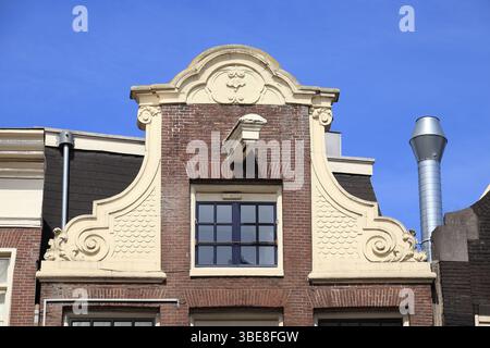 Extérieur du bâtiment historique avec pignon de cou décoré contre un ciel bleu à Amsterdam, rue Damrak, pays-Bas, mai 2025. Banque D'Images