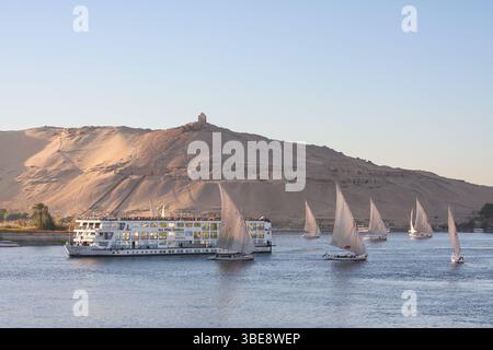 Egypte, Assouan, bateau de croisière et bateaux à voile traditionnels en bois ou Feluccas naviguant sur le Nil Banque D'Images