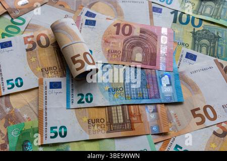 Billets en euros mélangés avec un billet de cinquante euros roulé. Une collection de billets en euros colorés, y compris des coupures de 50, 20 et 10 euros. Banque D'Images