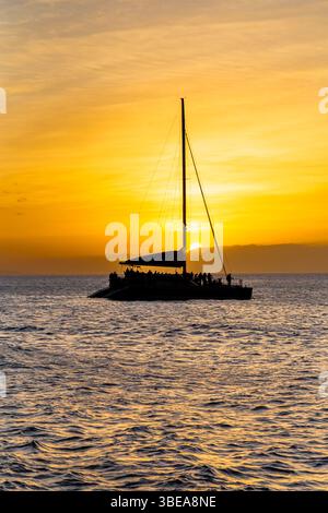 Maui, Hawaï, États-Unis - 7 avril 2022 : les passagers silhouettés profitent d'une croisière au coucher du soleil sur un catamaran, créant une scène sereine et pittoresque. Banque D'Images