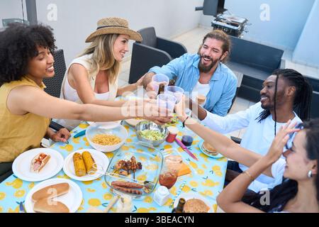 Heureux amis grillent pendant la partie barbecue sur le toit en dégustant des boissons et de la nourriture Banque D'Images