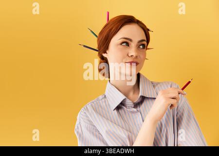 La jeune femme exprime son flair artistique avec des crayons colorés disposés de manière ludique dans ses cheveux. Banque D'Images