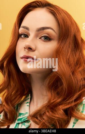 Jeune femme rayonnante avec des boucles rouges fluides met en valeur sa beauté et sa confiance dans un cadre animé. Banque D'Images
