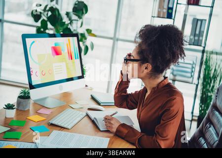 Jeune femme d'affaires professionnelle analysant des données sur ordinateur de bureau dans un espace de travail de bureau moderne bien éclairé Banque D'Images