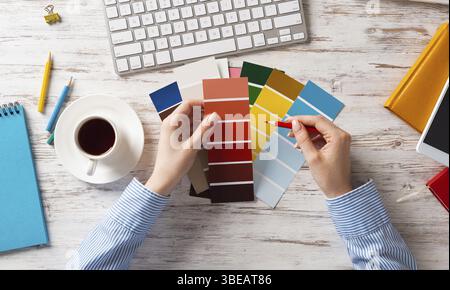 Concepteur Web choisissant des couleurs à partir de nuances au bureau en bois. Lieu de travail de bureau avec clavier d'ordinateur et tasse de café. Conception de l'interface utilisateur de mobi Banque D'Images