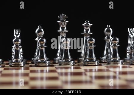 Figures d'échecs argentées debout sur un échiquier en bois. Jeu intellectuel et tactique. Concept d'entreprise de planification stratégique, de leadership et de travail d'équipe. Clos Banque D'Images