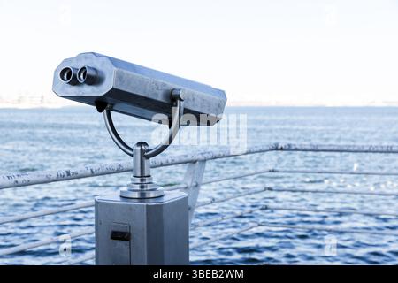 Jumelles publiques montées sur un support métallique sont positionnées pour offrir une vue panoramique sur l'océan, entourées par un horizon pittoresque et des eaux bleues claires, epit Banque D'Images