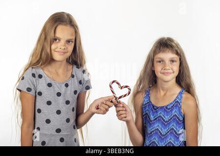 Deux jeunes filles a fait un coeur de deux sucettes et regarder dans le cadre Banque D'Images