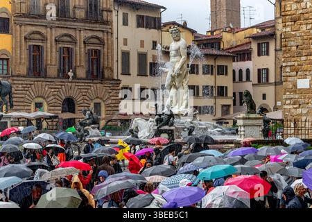 Foules de personnes abritant sous des parapluies regardant la fontaine de Neptune sous de fortes pluies sur la Piazza della Signoria à Florence, Italie Banque D'Images