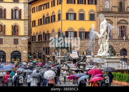 Foules de personnes abritant sous des parapluies regardant la fontaine de Neptune sous de fortes pluies sur la Piazza della Signoria à Florence, Italie Banque D'Images