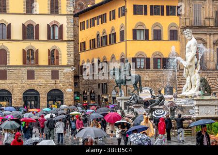 Foules de personnes abritant sous des parapluies regardant la fontaine de Neptune sous de fortes pluies sur la Piazza della Signoria à Florence, Italie Banque D'Images
