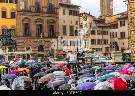 Foules de personnes abritant sous des parapluies regardant la fontaine de Neptune sous de fortes pluies sur la Piazza della Signoria à Florence, Italie Banque D'Images