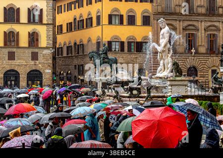 Foules de personnes abritant sous des parapluies regardant la fontaine de Neptune sous de fortes pluies sur la Piazza della Signoria à Florence, Italie Banque D'Images