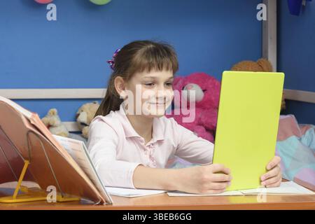 La jeune fille a fait ses devoirs et communique avec des amis via des appels vidéo Banque D'Images