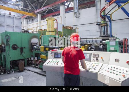 Travailleur derrière le tableau de bord dans l'atelier pour la production de profilés en aluminium. presse d'extrusion d'aluminium Banque D'Images