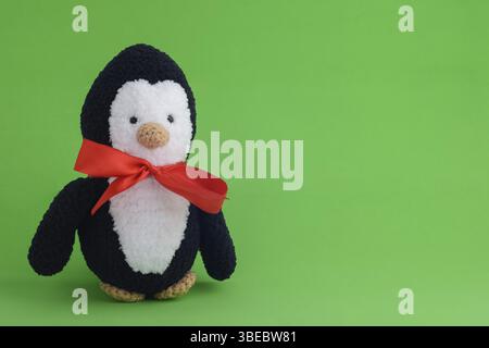 Pingouin en peluche tricoté sur fond vert Banque D'Images