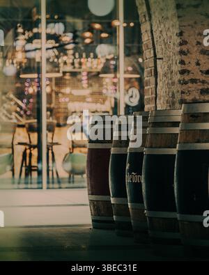 Tonneaux en bois au premier plan avec arrière-plan intérieur de restaurant flou, éclairage d'ambiance chaleureux avec effet bokeh Banque D'Images