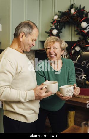 Photo de couple âgé des années 60 profitant de la vie à la cuisine avec des tasses de café. saint valentin des vieux couples amoureux. arrêtez la discrimination fondée sur l'âgisme. Banque D'Images