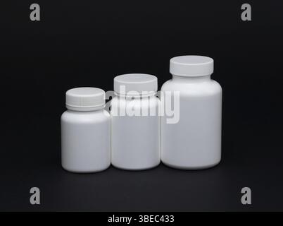 Pots de pilules en plastique blanc sur fond noir.Isolé Banque D'Images