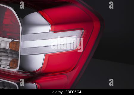 Gros plan des phares de voiture rouges sur le fond noir isolé. phare de voiture taillé Banque D'Images