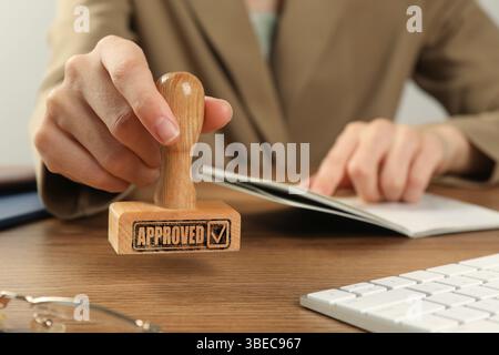 Approuvé. Femme tamponnant passeport à table, gros plan Banque D'Images