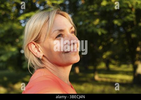 Portrait de femme blonde mature dans le parc le jour d'été du coucher du soleil. Banque D'Images