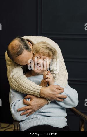 Portrait de vieux couple épouse et mari serrant et souriant. Fond bleu foncé. Heureux amoureux à la retraite. Arrêtez l'âgisme. . Banque D'Images