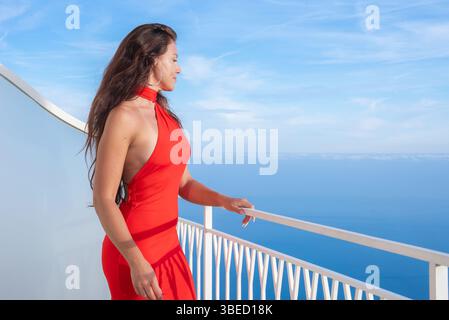 Femme en robe rouge sur balcon surplombant la mer Tyrrhénienne à Amalfi Banque D'Images