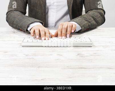 Gros plan des mains de femme tapant sur le clavier de l'ordinateur. Femme d'affaires travaillant au bureau. Femme d'entreprise en costume à son lieu de travail dans le bureau. Manager utilisant DIG Banque D'Images