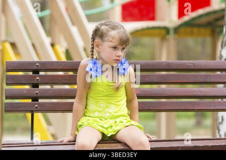 Offensé fille de cinq ans s'asseoir sur un banc et de pleurer Banque D'Images