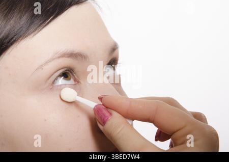 Maquilleur traite le maquillage sur le visage du modèle. Elle peint les ombres du modèle des paupières supérieures Banque D'Images