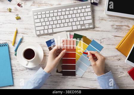 Concepteur Web choisissant des couleurs à partir de nuances au bureau en bois. Lieu de travail de bureau avec clavier d'ordinateur et tasse de café. Conception de l'interface utilisateur de mobi Banque D'Images