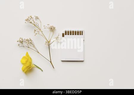 Carte mémoire blanche sur fond blanc avec des fleurs déposées. Concept de technologie durable respectueux de l'environnement. Extraction de pièces de chia sur mémoire ssd. L'avenir de la techn Banque D'Images