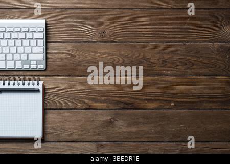 Vue du dessus de l'homme moderne de travail. Le bloc-notes à spirale et clavier de l'ordinateur sur la surface en bois brun. L'éducation, la créativité et l'innovation concept w Banque D'Images
