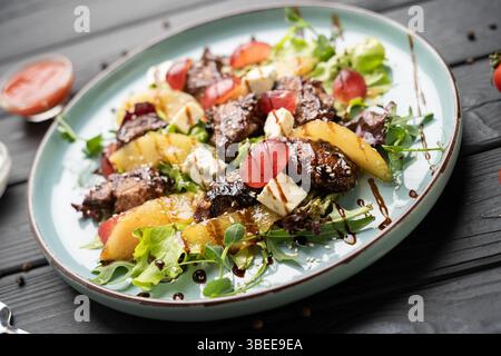 Salade gourmande avec tranches de poire caramélisées, foie de poulet grillé, fromage bleu, raisins frais, laitue, et bruine balsamique. Placage restaurant, elega Banque D'Images