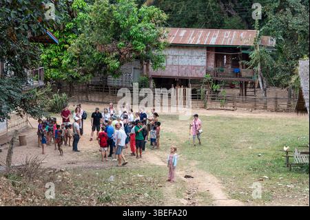 Un grand groupe de touristes en visite dirigé par un guide prenant une courte visite autour du village de Ban Paksit, un petit village isolé sur le fleuve Mékong dans le nord Banque D'Images
