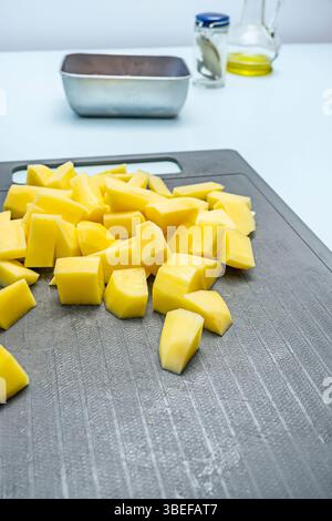 Pommes de terre pelées et hachées sur une planche à découper prête à cuire Banque D'Images