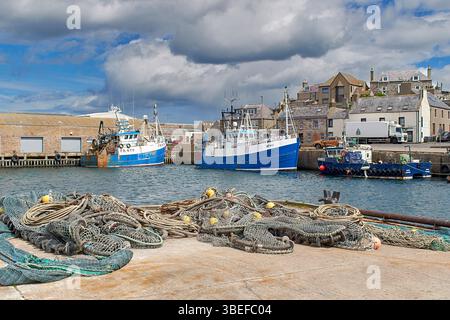 Macduff Aberdeenshire Écosse chalutiers bleus amarrés ou amarrés dans le port et filets de pêche sur le quai Banque D'Images