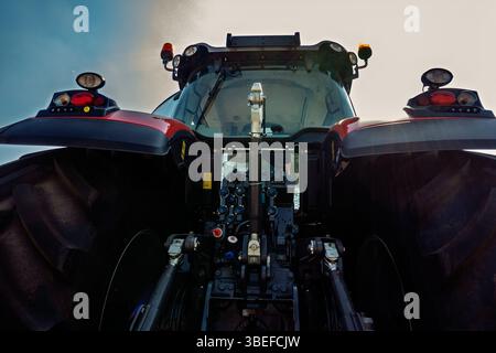 L'arrière du tracteur moderne avec de grandes roues dans le champ contre le ciel bleu. Banque D'Images
