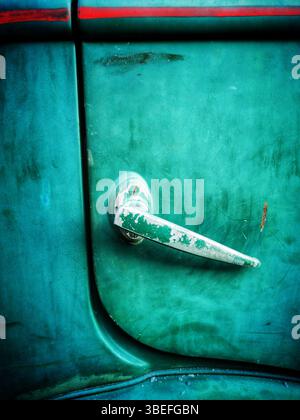 Une vue rapprochée d'une poignée de porte de voiture d'époque avec une surface altérée et une peinture vert éclatant. Banque D'Images